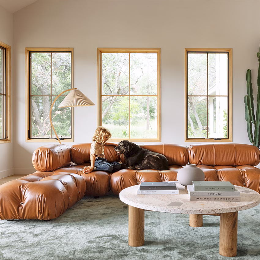 A caramel leather modular sofa and stone coffee table in a sunlit living room